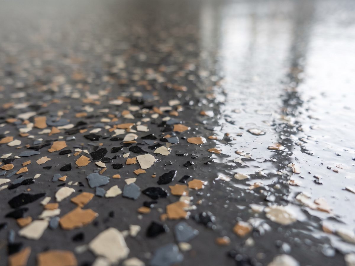 Close-up of a finished flake epoxy floor, individual charcoal, tan and off-white chips visible under the high-gloss topcoat